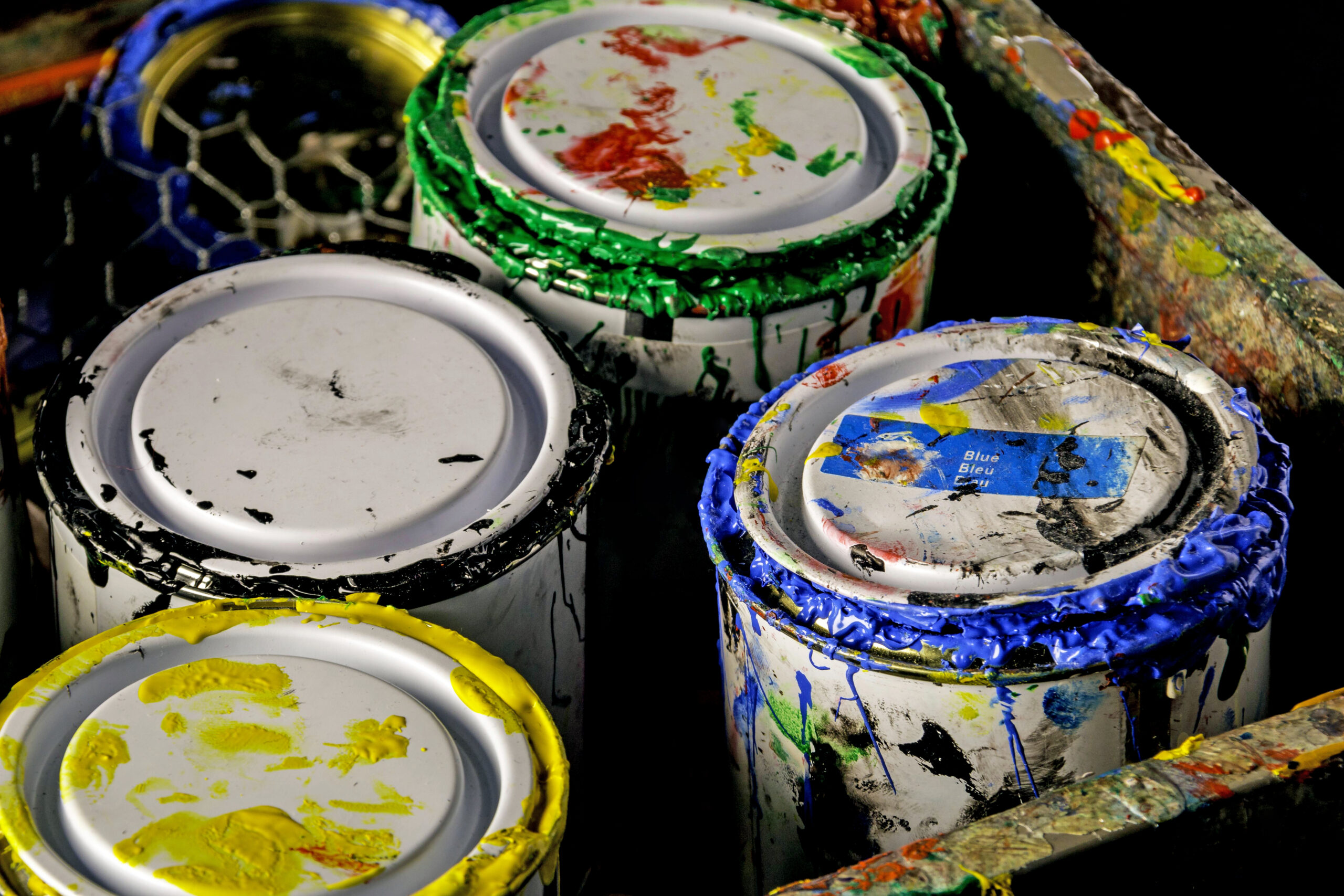Paint pots on a black background in a messy tray
